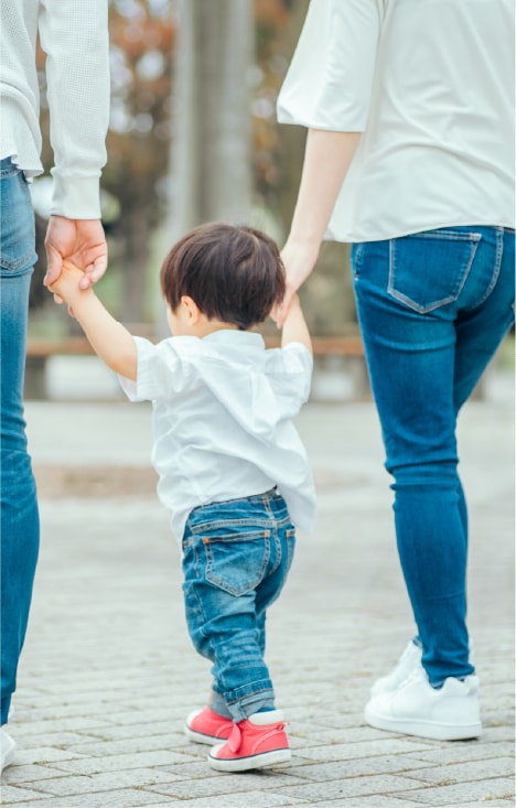保護者と手をつないで歩く小さなお子さま