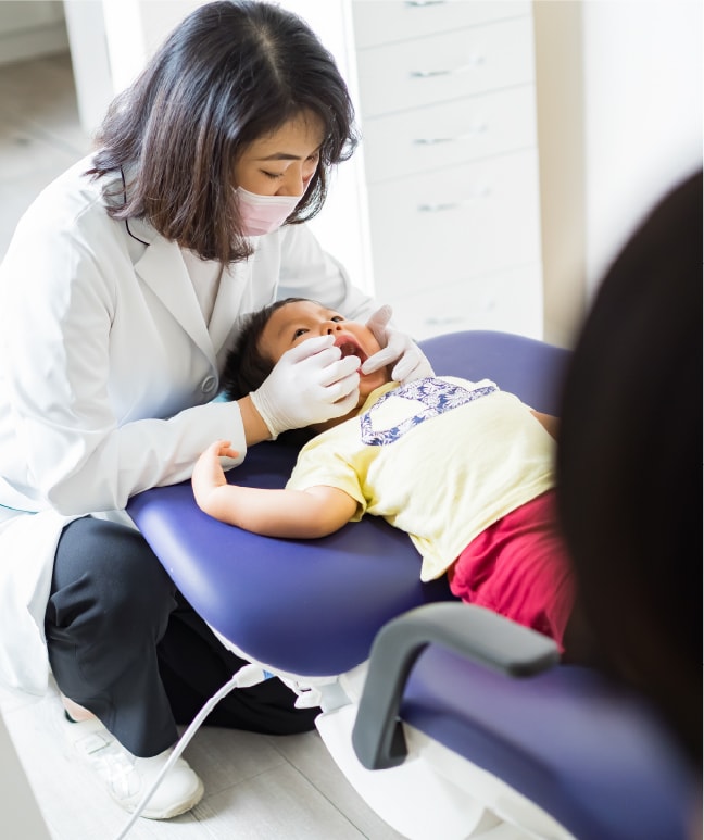 お子さまのお口の中をやさしく診察する歯科医師